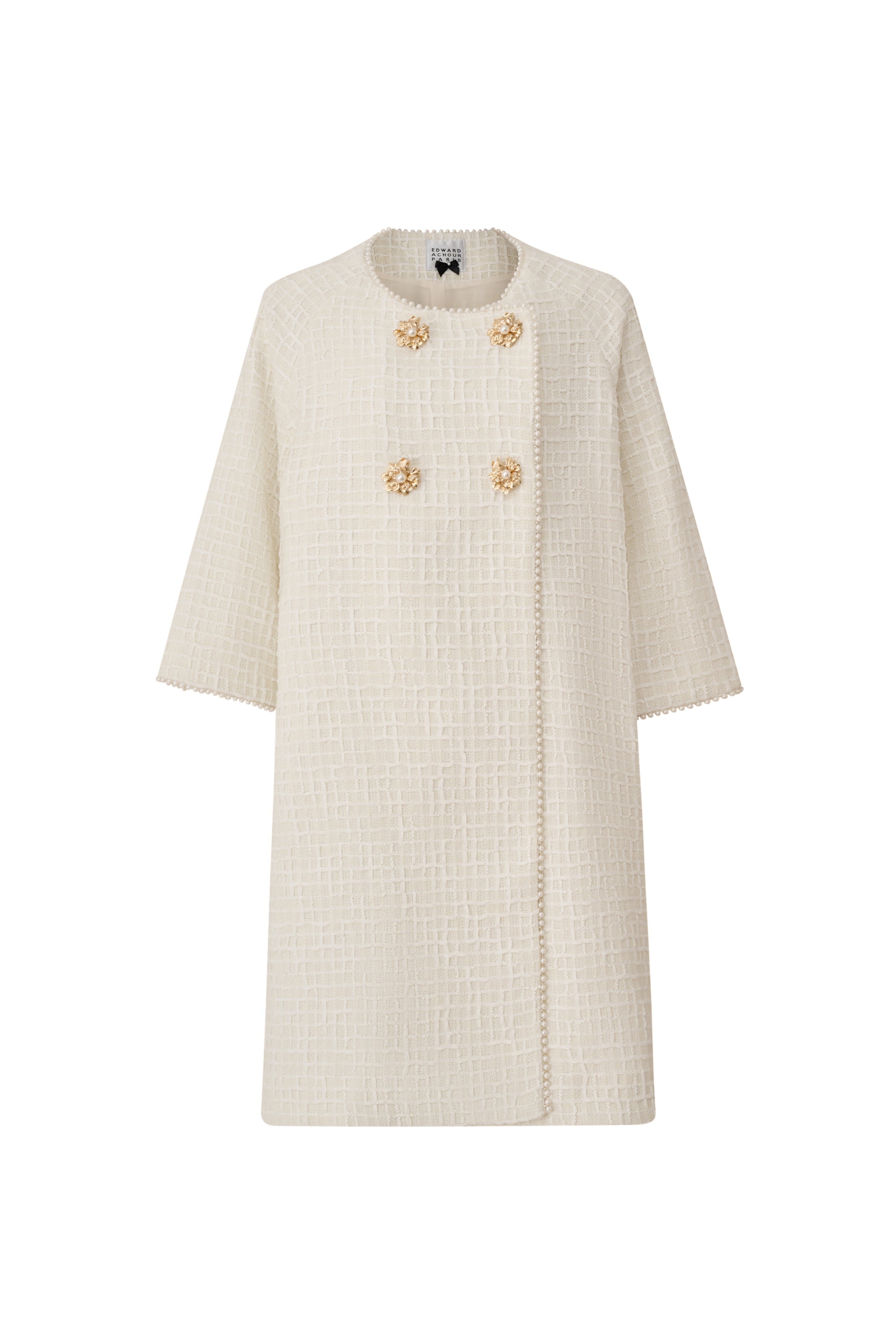 Front view of an ivory oversized double-breasted A-line coat with pearl details by Edward Achour.
