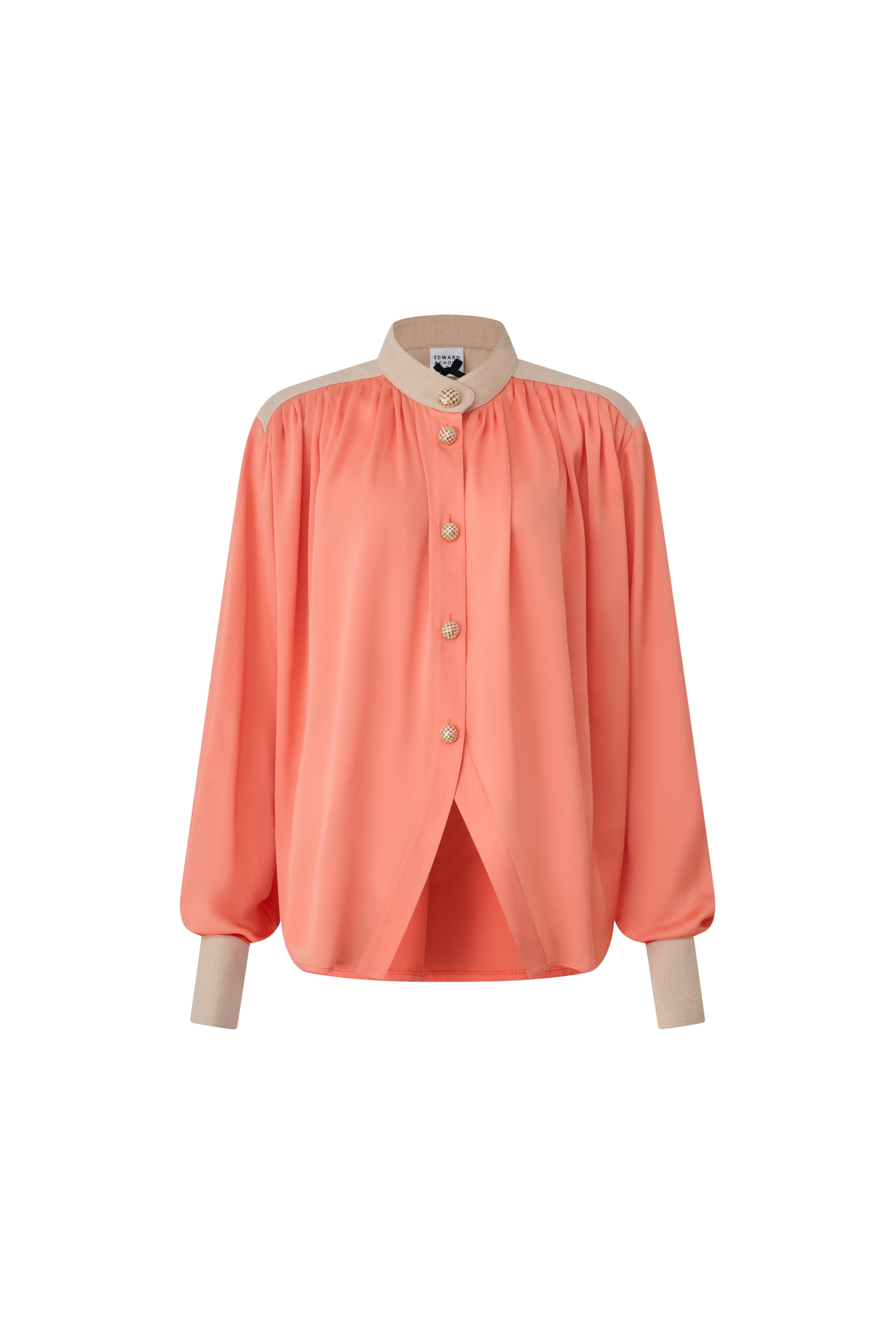 Front view of a coral orange pleated blouse with beige collar and cuffs by Edward Achour Paris.