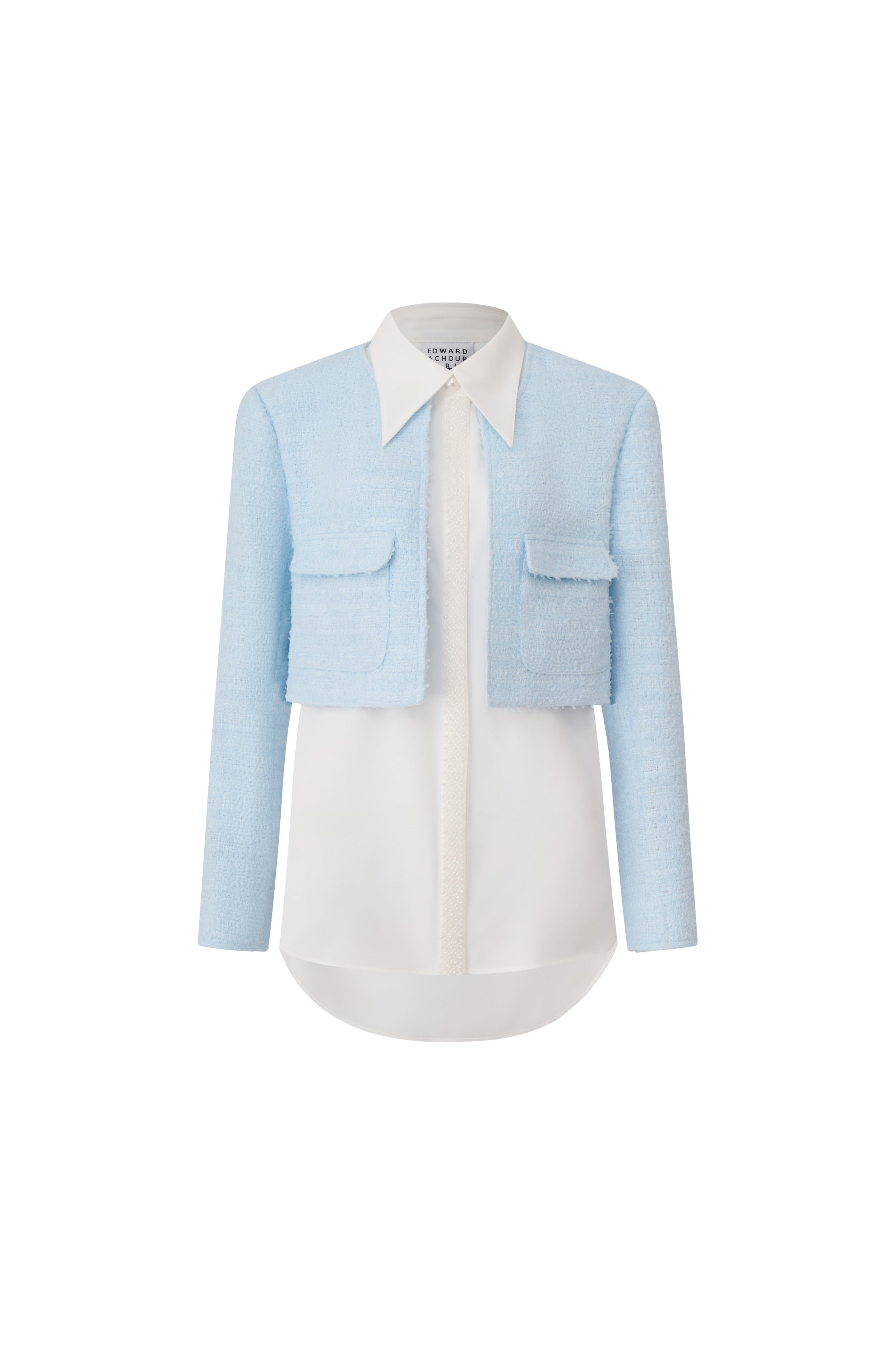 Front view of a light blue cropped tweed jacket layered over a white long-line shirt by Edward Achour.