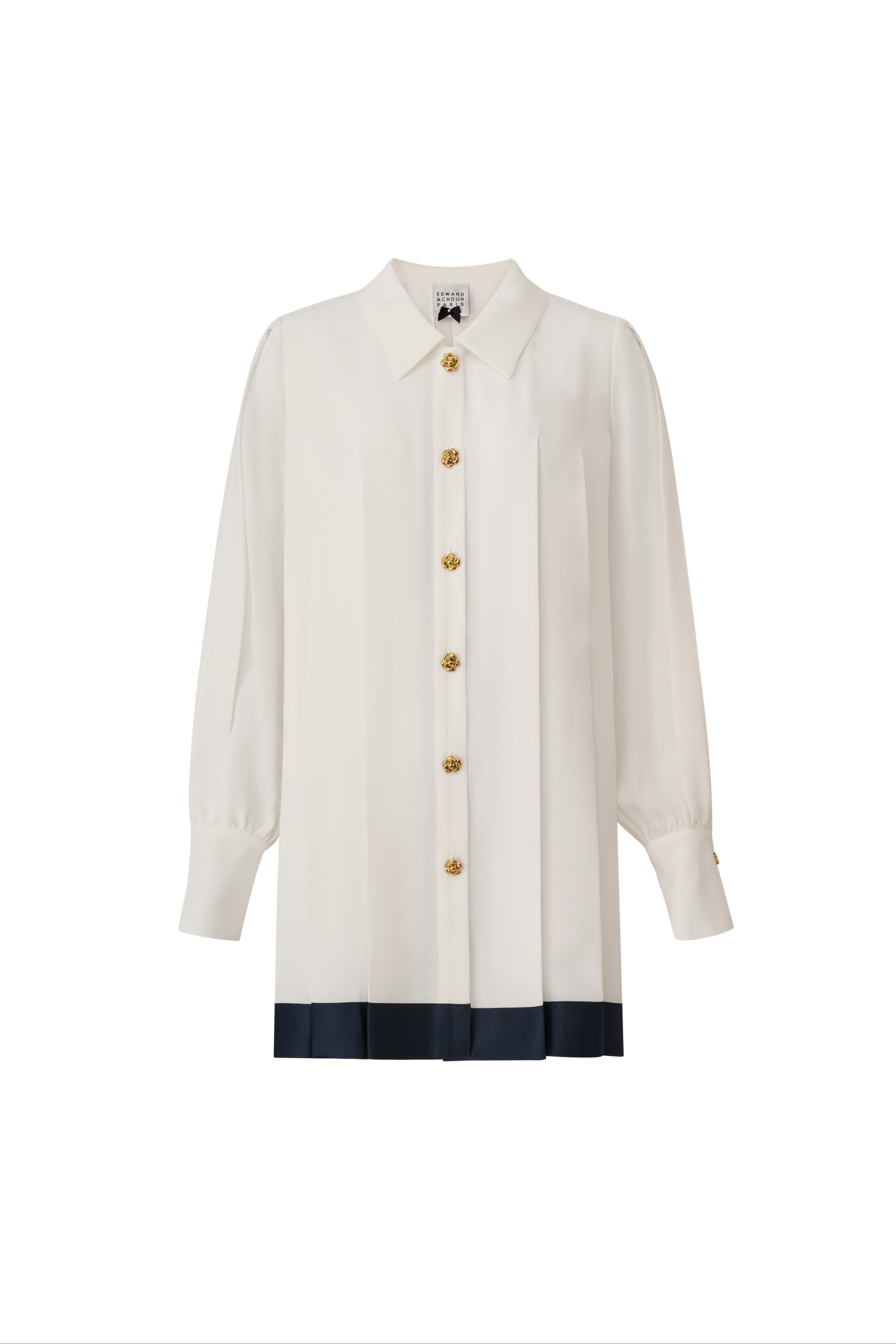 Front view of a white long-sleeve blouse with a navy pleated bottom edge and gold buttons by Edward Achour Paris.